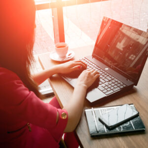 close-up office desk. Workspace with girl's hands, laptop, coffee cup. Business woman.