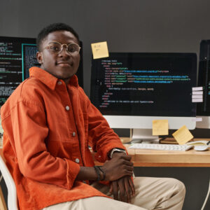 Young IT support manager looking at camera while sitting by workplace