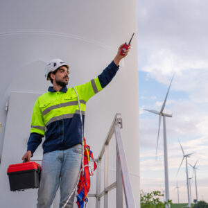 Engineer wearing uniform hold equipment box inspection work in wind turbine farms rotation to generate electricity energy.