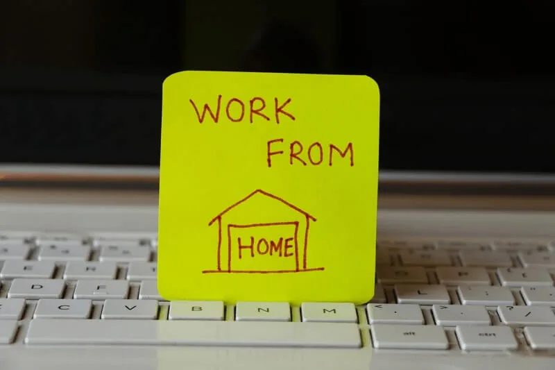Sticky note reading work from home resting on a computer keyboard