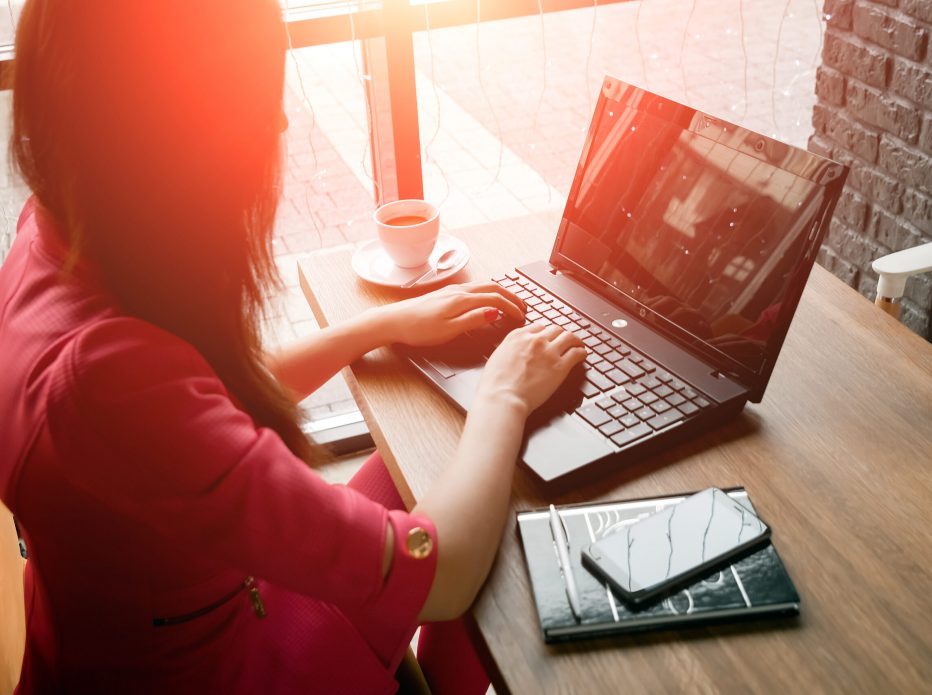 close-up office desk. Workspace with girl's hands, laptop, coffee cup. Business woman.