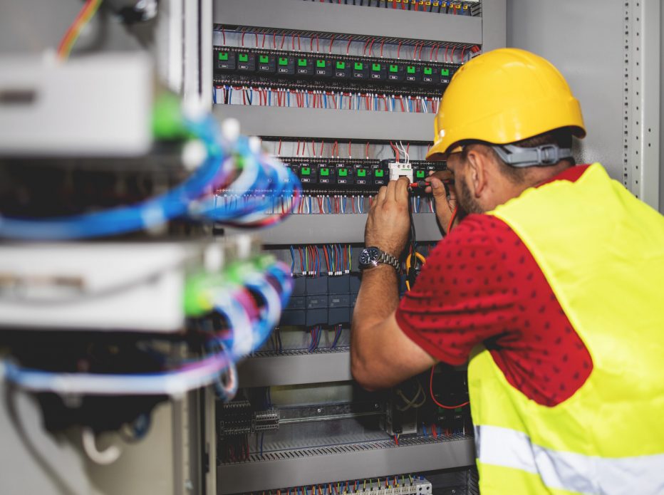 Electrician engineer work tester measuring voltage and current of power electric line in electical cabinet control.