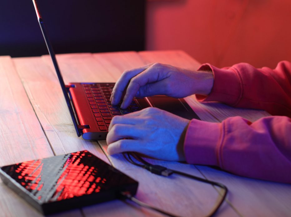 laptop with attached optical drive on the table in front of a person on a colored background