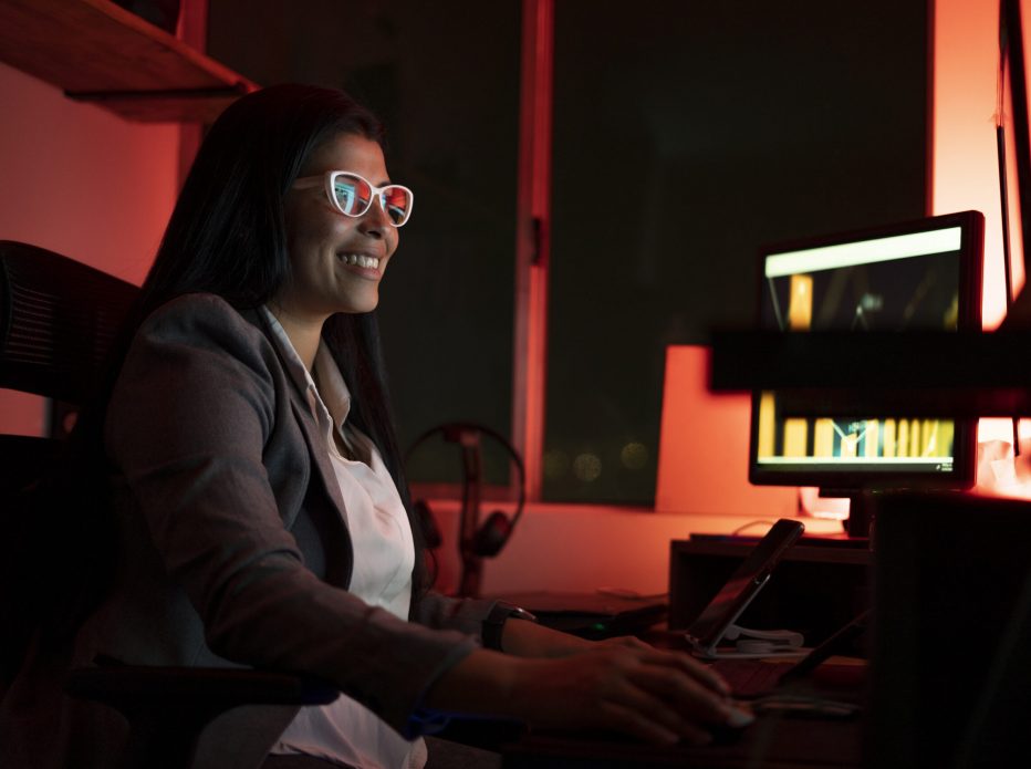 Photo of a young businesswoman using a computer during a work night doing her reports